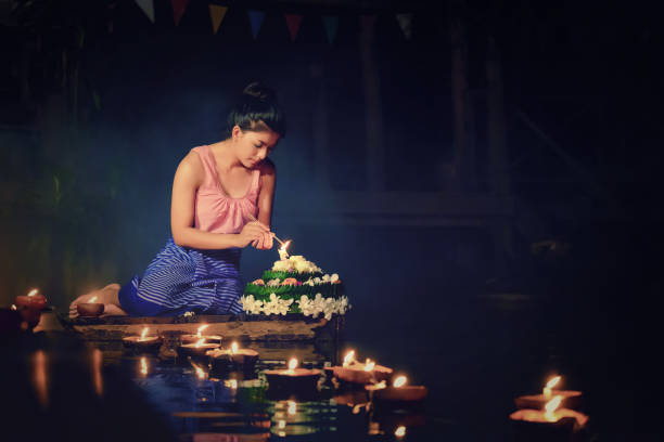 istock Young Woman Burning Incense Sticks By Diyas Floating On Pond 890957224