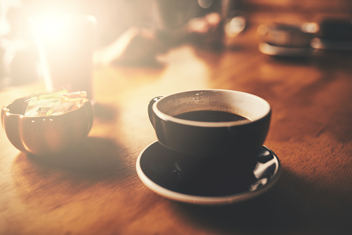 Shot of a cup of freshly brewed coffee on a wooden table of a restaurant