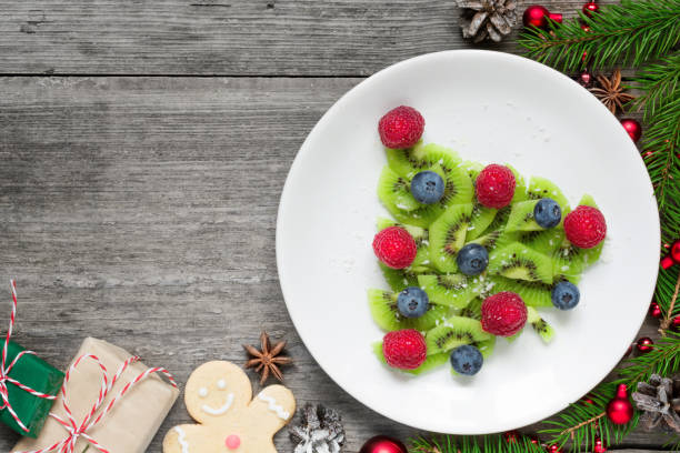 istock kiwi christmas tree with fir tree branches and gift boxes over rustic wooden table. funny food idea for kids 890980520