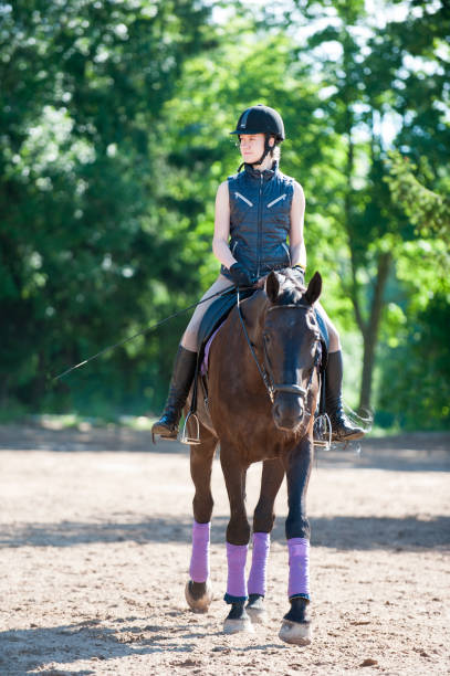 istock Young lady riding a horse at equestrian school. Training process 890994216