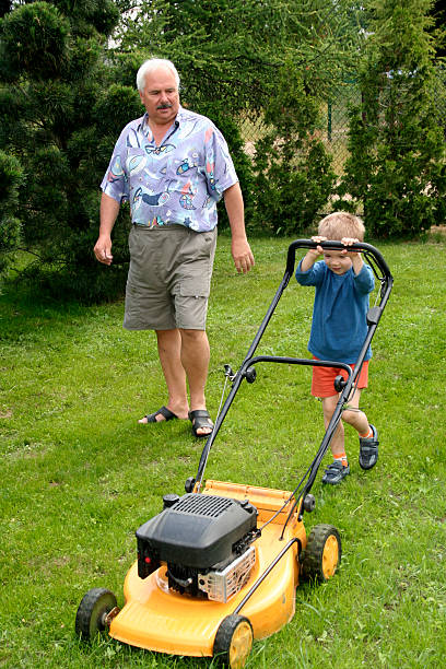 istock Grandfather and grandson mowing grass 89101762