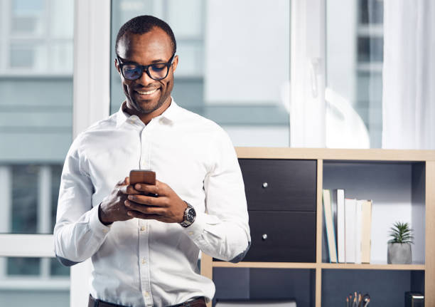 Cheerful stylish businessman is using his smartphone