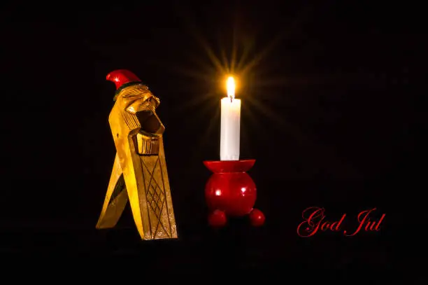 Christmas greetings in Swedish on a Norwegian Gnome Handcarved Wooden Nut Cracker, together with a candlelight on a typical red wooden candlestick.