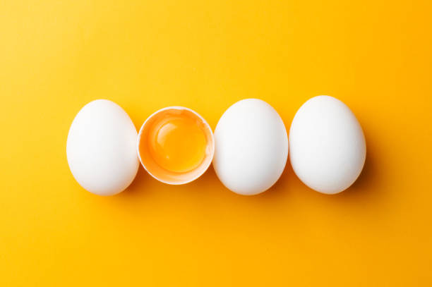 istock White eggs and egg yolk on the yellow background. topview 891103058