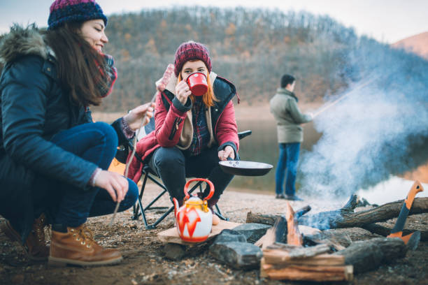 campeurs à côté du feu de camp préparer la nourriture - pêche activité de plein air photos et images de collection