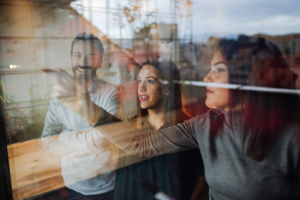 Making plans on a transparent wipe board Photo of a young woman writing on a transparent wipe board and thinking of a solution for her work-related problems, while her coworkers are participating writing on chalk board stock pictures, royalty-free photos & images