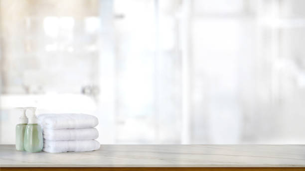 istock Ceramic soap green bottles and white cotton towels on a marble counter table inside a bright bathroom background. 891120982