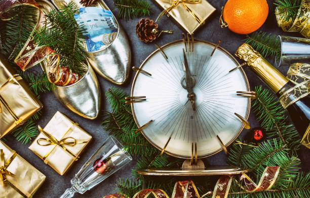 new year celebration. traditional put money to shoe for have money en new year. flat lay composition with vintage clock, shoes with chilean money pesos, champagne, christmas decorations - argentina mexican pesos currency finance imagens e fotografias de stock