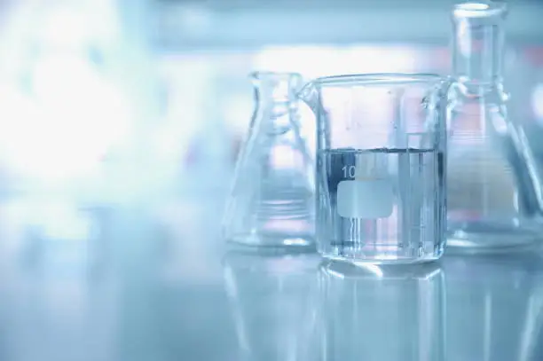 Photo of experiment water in beaker and flask in chemistry science laboratory background