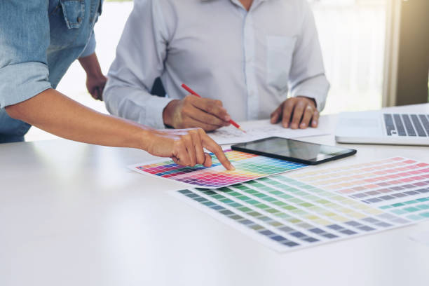 istock Young colleagues designers working together on a creative project and color samples for selection, Color swatch samples, Brainstorming Planning Partnership, creative graphic design working desktop 891126570