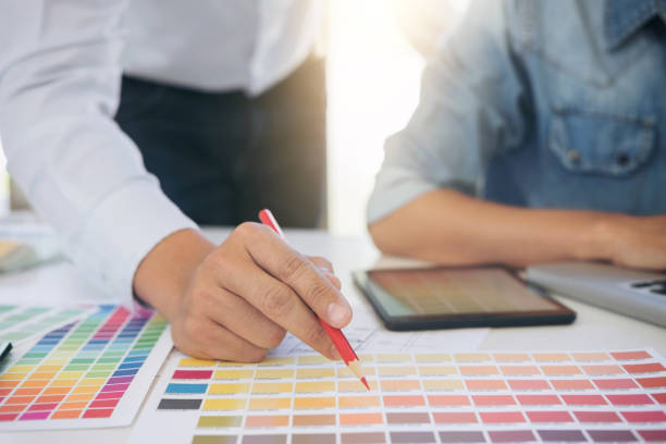 istock Two interior design or graphic designer at work on project of architecture drawing with work tools and color swatches, colour chart, color samples for selection, renovation and technology concept 891126572