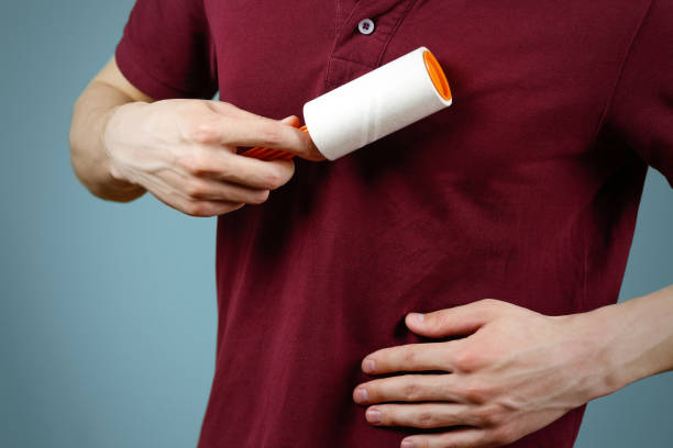 istock A man cleans the t-shirt sticky roller. Closeup. Isolated 891128994