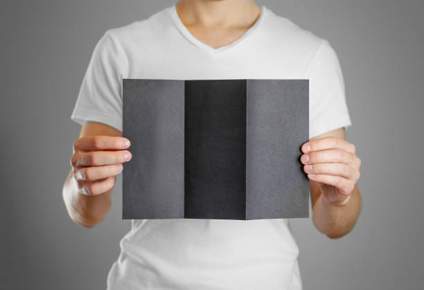 istock A man holds a black paper in his hand. Shows a blank flyer. Isolated 891129026