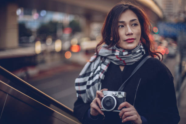 Young beautiful woman standing on the street with camera - photographic equipment