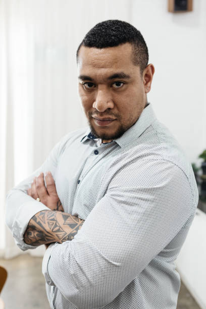 istock Serious expression of a Pacific Islander man with folded arms looking into camera 891150396