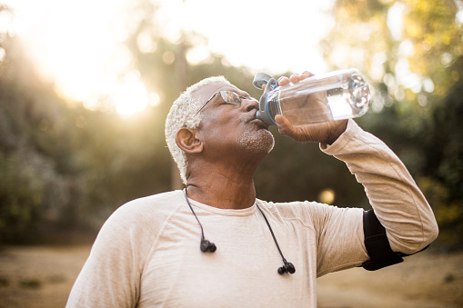 A senior African American Man enjoying refreshing water after a workout