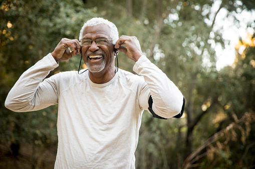 A senior African American Man gets his headphones ready during a workout