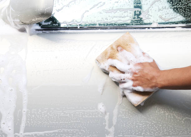 istock hand with yellow sponge washing car 891184076