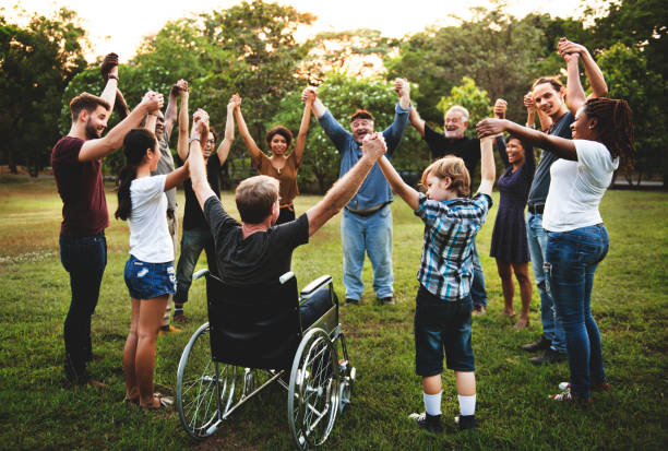 Group of people holding hand together in the park Group of people holding hand together in the park wheelchair photos stock pictures, royalty-free photos & images
