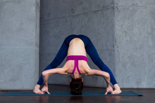 istock Full-length front view of sporty young woman practicing yoga doing standing straddle forward bend pose, Prasarita Padottanasana, working-out indoors 891189706
