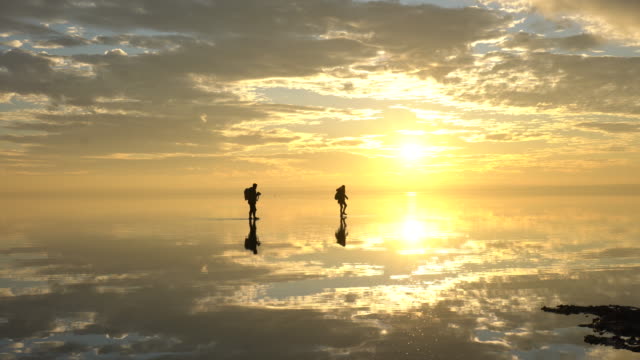 Traveler couple having fun walking on salt lake at sunset