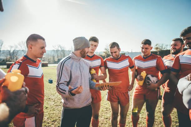 Coach talking to players Young and strong rugby team on the field, coach talking to his players. rugby team stock pictures, royalty-free photos & images