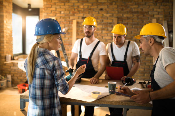 istock Female building contractor giving instructions to group of workers on construction site. 891280820