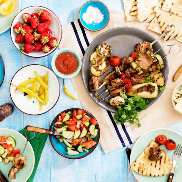 istock Dinner table with shish kebab, grilled vegetables, salad, snacks and strawberries 891281038