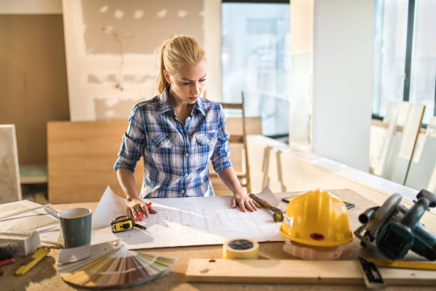 empreiteiro jovem examinando o projeto habitacional no canteiro de obras. - architect home improvement house blueprint - fotografias e filmes do acervo