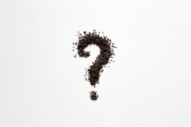 istock Question mark created from black, dried, loose tea on the white table. Choice of the best sort and quality tea. Empty place for a text. 891281368
