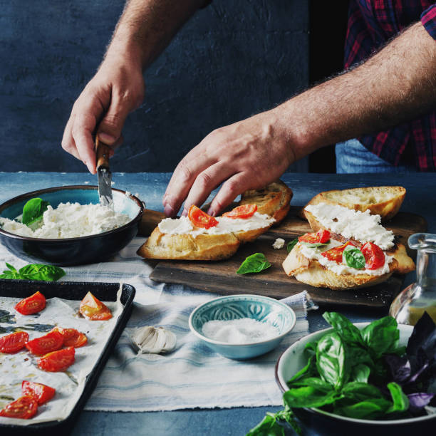 istock Man preparing Italian bruschetta with baked tomatoes, basil and cheese 891281460