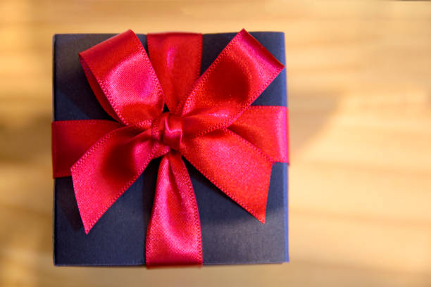 istock Gift box of red ribbon over wooden table. 891284496