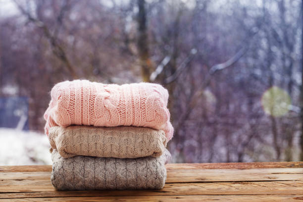 istock Stack of knitted clothes on wooden tableon winter nature background. 891284598