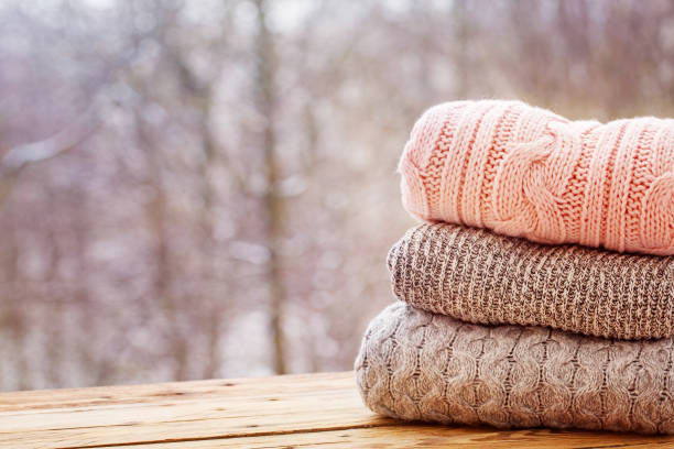 istock Stack of knitted clothes on wooden tableon winter nature background. 891284640