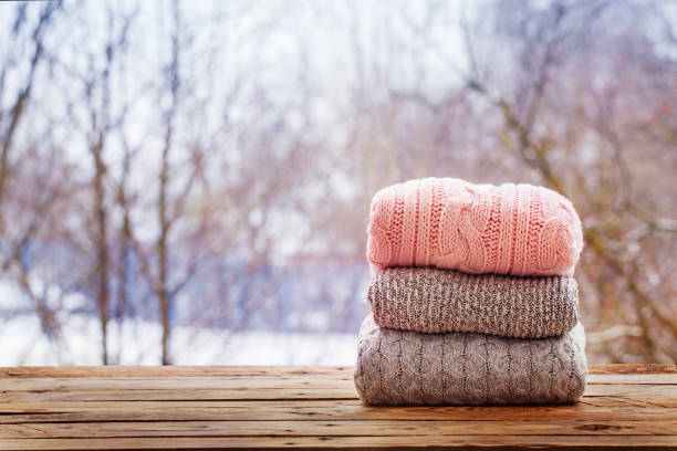 istock Stack of knitted clothes on wooden tableon winter nature background. 891284698