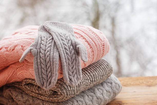 istock Stack of knitted clothes on wooden tableon winter nature background. 891284716