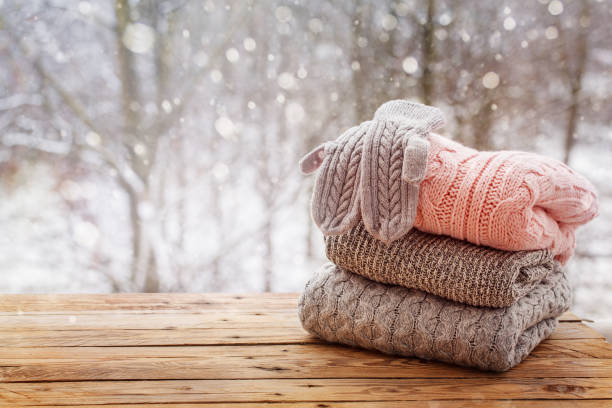 istock Stack of knitted clothes on wooden tableon winter nature background. 891288802