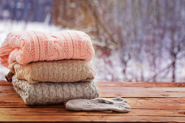 istock Stack of knitted clothes on wooden tableon winter nature background. 891289040