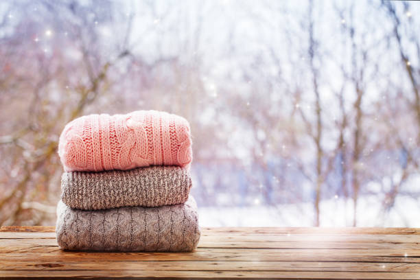 istock Stack of knitted clothes on wooden tableon winter nature background. 891289098
