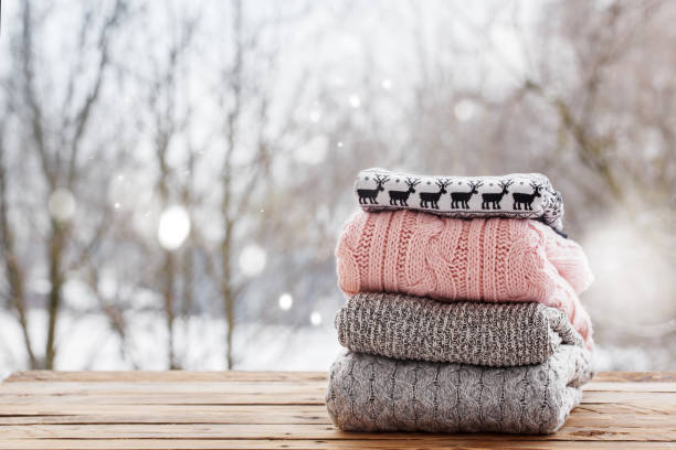 istock Stack of knitted clothes on wooden tableon winter nature background. 891289280