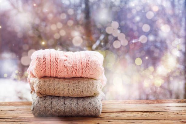 istock Stack of knitted clothes on wooden tableon winter nature background. 891289344