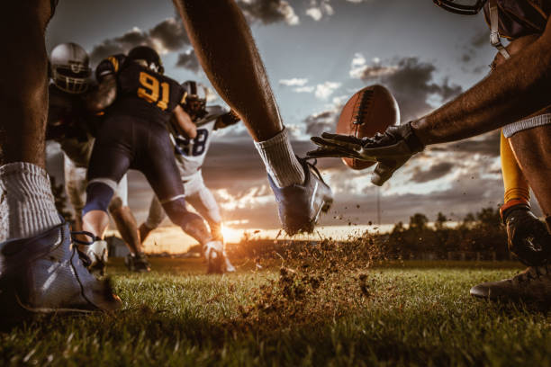 Kick off on American football match at sunset! Unrecognizable American football player making a kick off during the match on a playing field. football league stock pictures, royalty-free photos & images