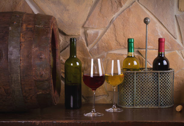 istock Red and white wine beside old cask in wine cellar 891307852