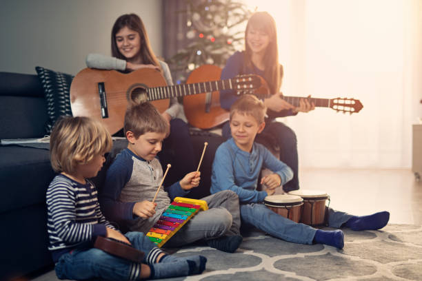 niños practicando villancicos junto a árbol de navidad - sunny cantante fotografías e imágenes de stock