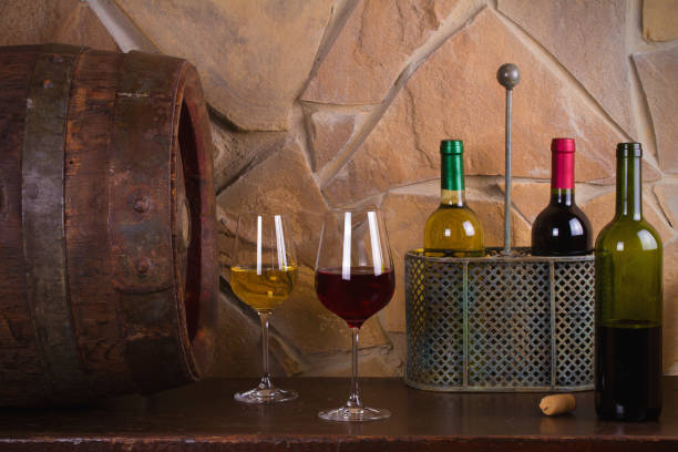 istock Red and white wine beside old cask in wine cellar 891310782