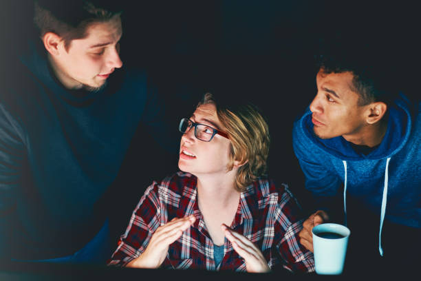 istock Three serious young people study computer monitor at night 891318176