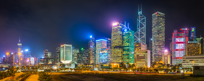 Panoramic view along the harbour waterfront to the glittering neon skyscrapers of Hong Kong Island, China.