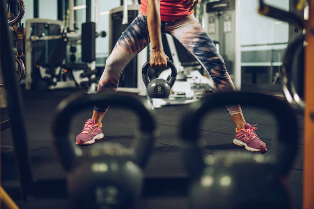 istock Unrecognizable athletic woman exercising with kettle bell in a gym. 891325872