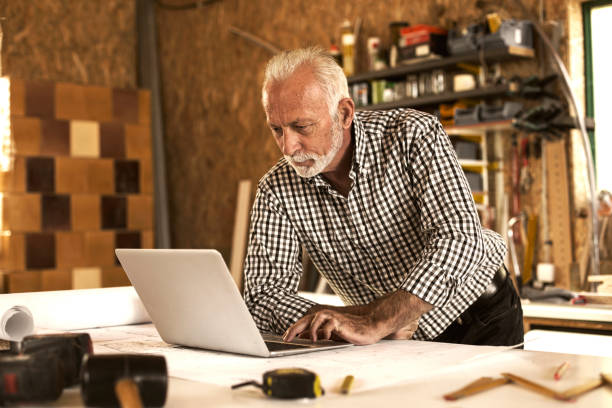 istock Mature designer in his workshop on laptop 891326304