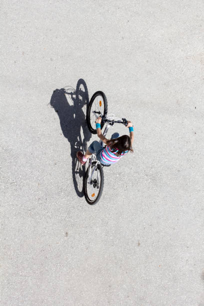 istock Little girl riding a bicycle on asphalt, long shadow, top view 891326680